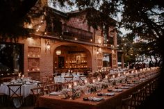 a long table is set with candles and place settings in front of an old building