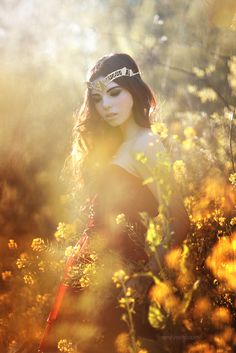 a woman standing in the middle of a field with sun shining on her face and hair