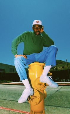 a man sitting on top of a yellow fire hydrant