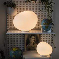 a couple of lights sitting on top of a white shelf next to a potted plant