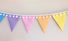 a colorful bunting banner with pom - poms hanging from it's sides