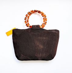 a brown purse sitting on top of a white table next to a yellow and orange cord