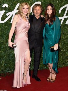 three people standing next to each other on a red carpet with the words gq written on it