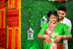 a man and woman standing next to each other in front of a wall with decorations