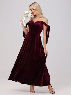 a woman in a long velvet dress holding a bouquet of flowers and posing for the camera