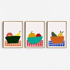 three framed art prints depicting fruits and vegetables on a white wall above a red checkered table cloth