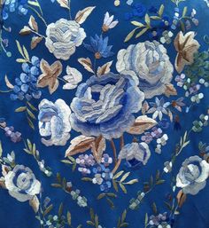 an embroidered blue jacket with white flowers and leaves on the front, along with other floral appliques