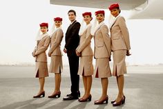 a group of people standing next to each other in front of an airplane