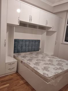 an empty bed in a room with white cupboards