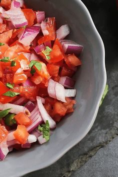 a close up of a bowl of food with onions and carrots in it on a table