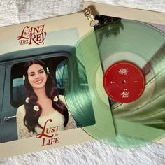 a green vinyl record sitting on top of a white blanket next to an album cover