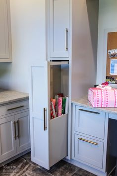 a kitchen with white cabinets and marble counter tops