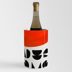 a bottle of wine in a cup with an orange and black design on it's side