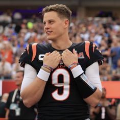 a football player standing in front of a crowd with his hands clasped to his chest