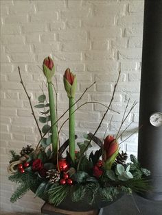 a vase filled with flowers and greenery next to a brick wall