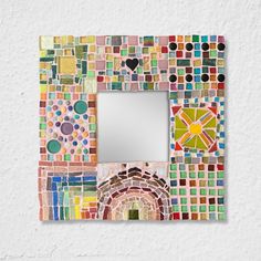 a multicolored mosaic tile frame with a mirror on the wall above it that has a heart shaped hole in the middle