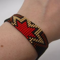 a person wearing a red and black beaded bracelet on their arm with gold beads