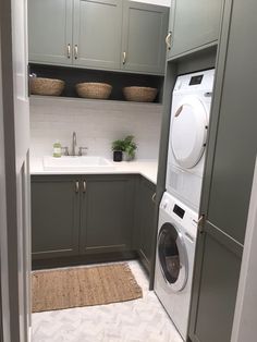 a washer and dryer in a small laundry room with green cupboards on the wall