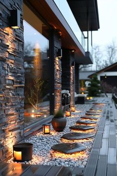 some lights are lit up on the side of a building with stones and gravel around it