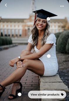 a woman in a graduation cap and gown sitting on a brick wall with her legs crossed