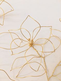 gold wire work with flowers and leaves on a white surface