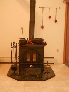 an old fashioned stove in a room with white walls and tile flooring on the ground