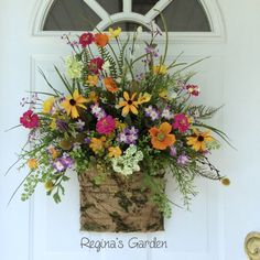 a basket filled with flowers sitting on top of a door