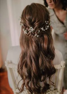 the back of a woman's head with long hair and flowers in her hair