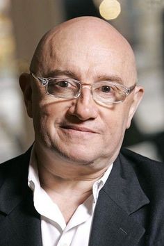 black and white photograph of a bald man wearing glasses with his head tilted to the side