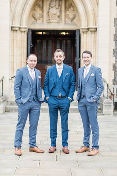 three men in blue suits standing on the steps of an old building with a doorway behind them