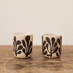 two black and white cups sitting on top of a wooden table