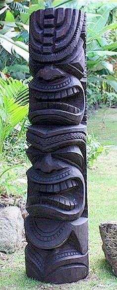 a tall stack of tires sitting on top of a lush green field next to rocks