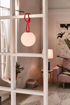 a living room filled with furniture and a white lamp hanging from the side of a window