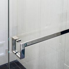 a glass shower door with chrome handles in a bathroom