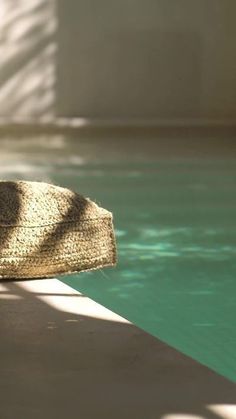 an umbrella sitting on the edge of a swimming pool next to a sunlit window