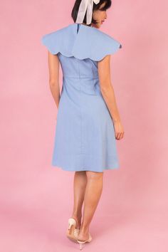 The Aida Dress is a versatile and stylish choice for any occasion. Made from a comfortable and stretchy light blue solid cotton blend fabric, this dress features a V-shaped neckline with an oversized scalloped collar, short fitted sleeves, and a knee length skirt. The hidden back zipper and non-functional buttons add a touch of detail to the classic design. Perfect for day or night, this dress offers a flattering fit and effortless elegance Fitted Cotton Midi Dress With Flutter Sleeves, Summer Dresses With Scalloped Edges And Short Sleeves, Knee-length Cotton Short Sleeve Dress, Light Blue Cotton Flutter Sleeve Dress, Light Blue Cotton Dress With Flutter Sleeves, Cotton Dresses With Scalloped Edges And Short Sleeves, Light Blue Cotton Midi Dress With Ruffles, Spring Short Sleeve Dress With Scalloped Edges, Light Blue Cotton Midi Dress With Short Sleeves