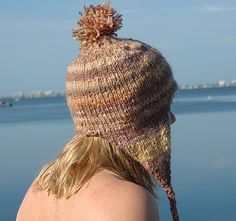 a woman wearing a knitted hat looking out at the water