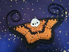 a crocheted bag with a skull on it sitting on a blue surface surrounded by stars