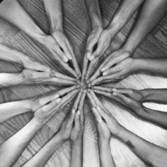 a group of people's hands in the middle of a circle on top of a wooden table