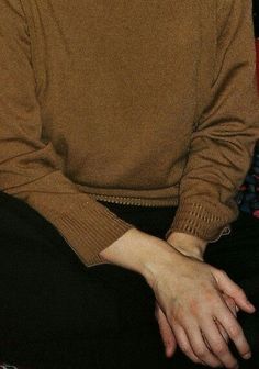 a man sitting down wearing a brown sweater