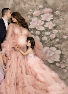 a family posing for a photo in front of a floral wallpapered backdrop with pink flowers