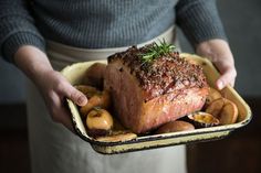 a person holding a tray with meat and potatoes