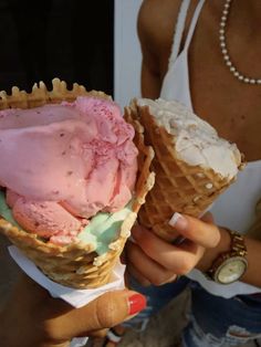 a woman holding two cones of ice cream in her left hand and another one on the other side