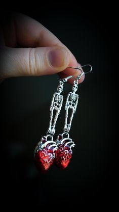 Spooky Scary Skeleton Earrings w/ Blood Red Anatomic Heart Charms, Gothic Dangles, Human Heart Jewelry, Boo Basket Gifts, Silver Skeletons <3 Spooky, scary skeletons are here! And they  brought something with them. Bloody red anatomical hearts. These are going to enhance your Fall wardrobe and impress even the most gothic of babes.  Perhaps slip these in a Boo Basket? These goth girl dangles are ready to ship, and come with lots of fun packaging. Red enamel dangles measure approx. 3" in total drop length.  Total width of anatomical heart is approx. .55" Set on silver-plated ear wires. These are great for most ears, but I cannot be held responsible for any severe metal allergies. I do not know what the charms of made of, but they are not real silver. Colors vary per monitor settings. Store Skeleton Earrings, Human Heart, Anatomical Heart, Spooky Scary, Heart Jewelry, Skeleton, Heart Charm, Crystal Jewelry, My Jewellery