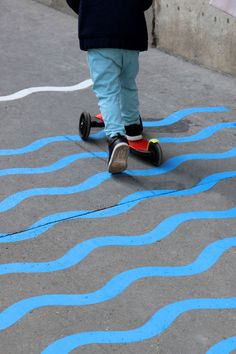 a person riding a skateboard on a painted street with blue lines in the pavement