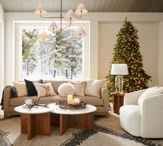 a living room filled with furniture and a christmas tree in the window sill behind it