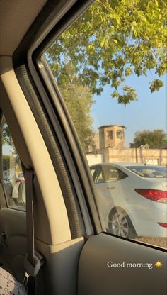 the rear view mirror of a car with cars parked in front of it and trees