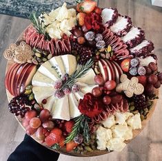 a wooden platter filled with cheese, fruit and crackers