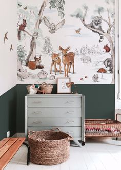 a baby's room with deer wallpaper and baskets on the floor next to it