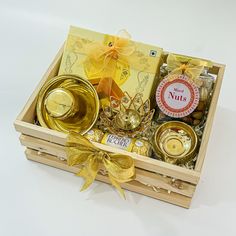 a wooden box filled with golden items on top of a white tablecloth covered floor